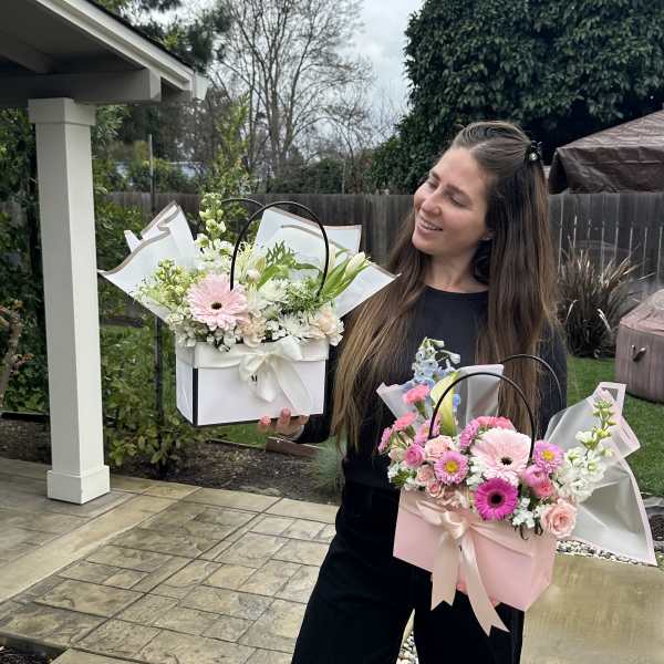 Woman holding two pastel flower gift boxes outdoors