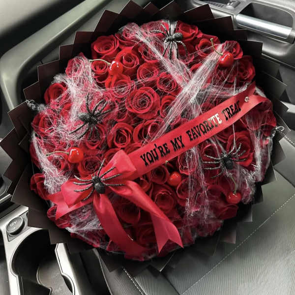 Red rose bouquet with spider decorations and a ribbon in a car seat
