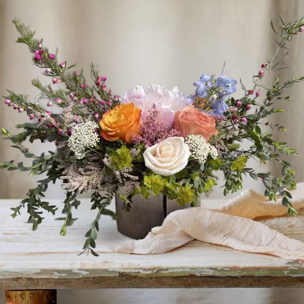 Mixed bouquet of roses and pastel blooms in a dark vase