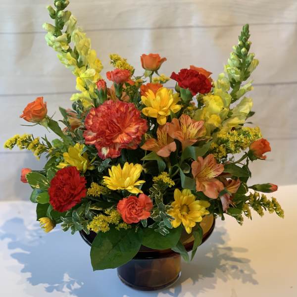 Colorful mixed flower arrangement in a brown glass vase