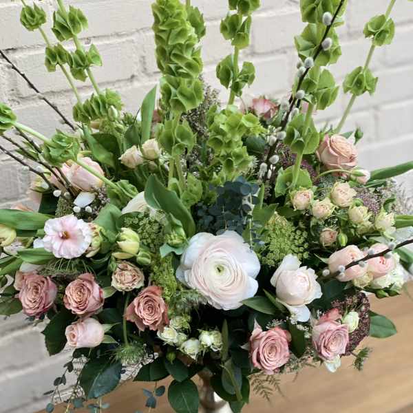 Tall bouquet of pink and white roses with green blooms in a silver vase