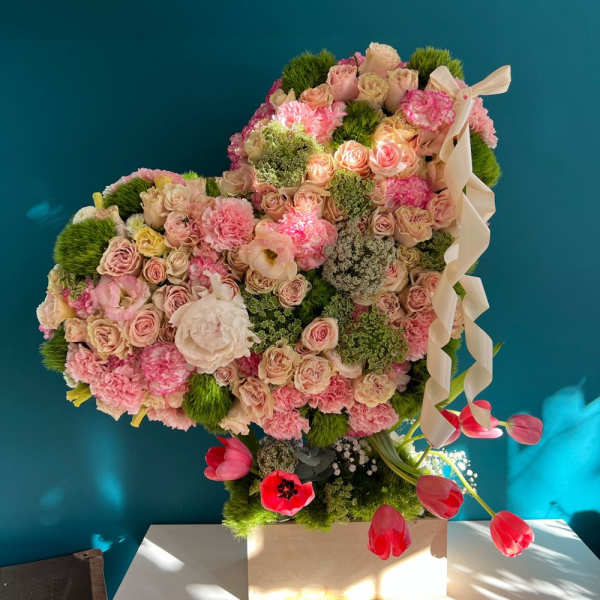 Heart-shaped floral arrangement with pink roses and carnations on a pedestal