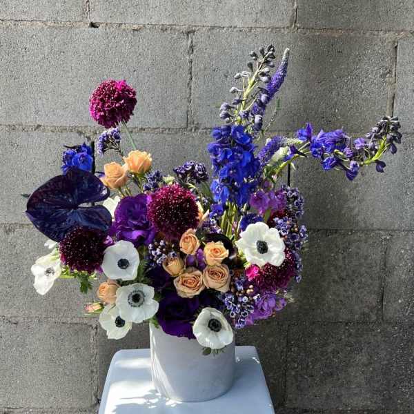 Purple and white floral arrangement in a white vase