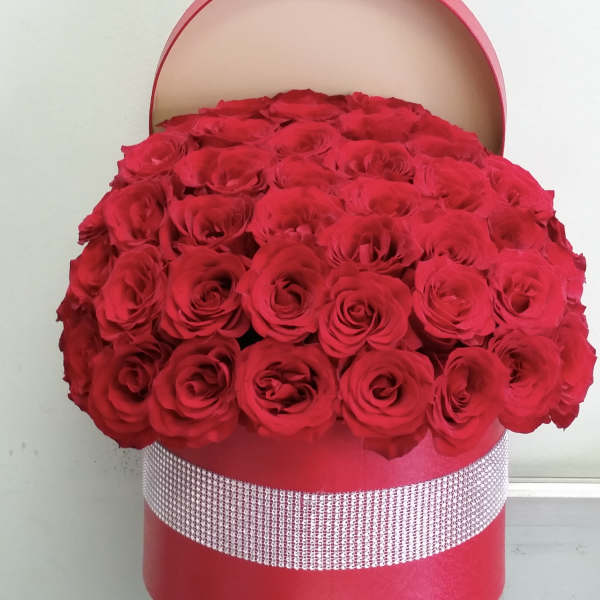 Large red rose arrangement in a round pink hat box