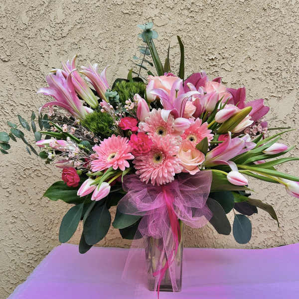 Pink mixed bouquet in a clear vase with a tulle bow