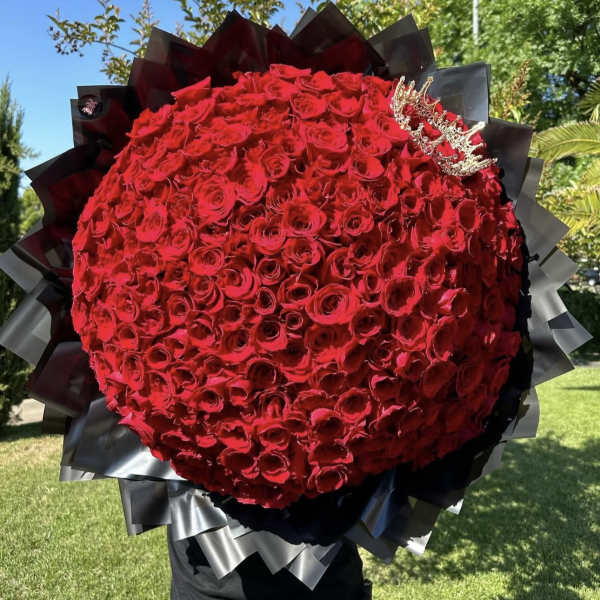 Large round bouquet of red roses with black wrapping and a small crown