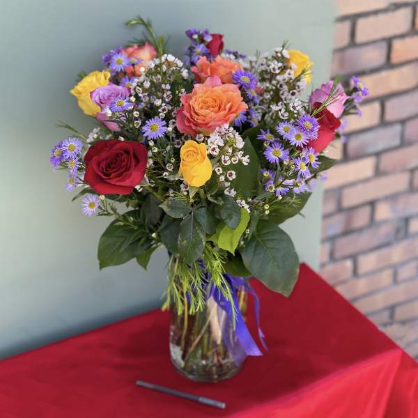 Mixed bouquet of roses and purple daisies in a glass vase