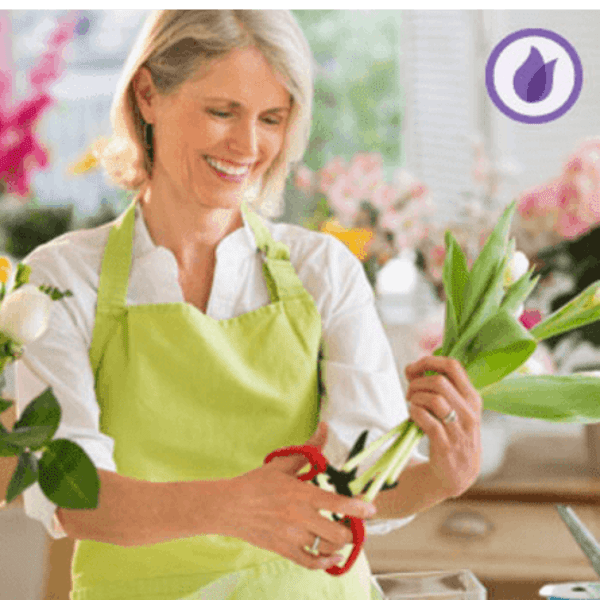 Woman in a green apron trimming flower stems in a shop