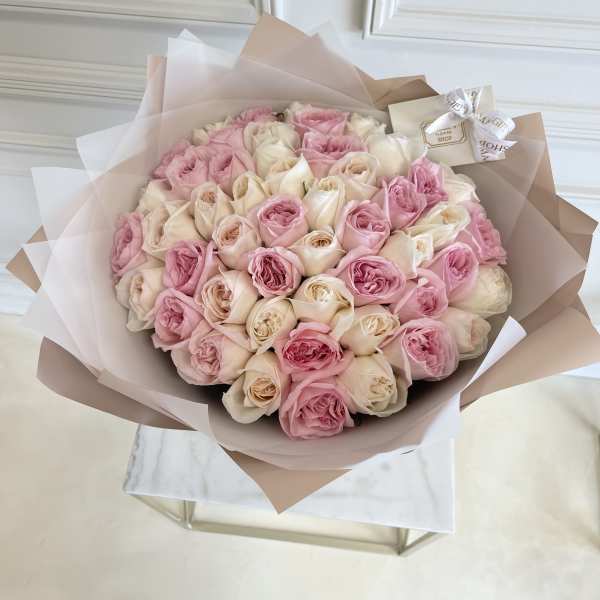 Large bouquet of pink and cream roses wrapped in blush paper