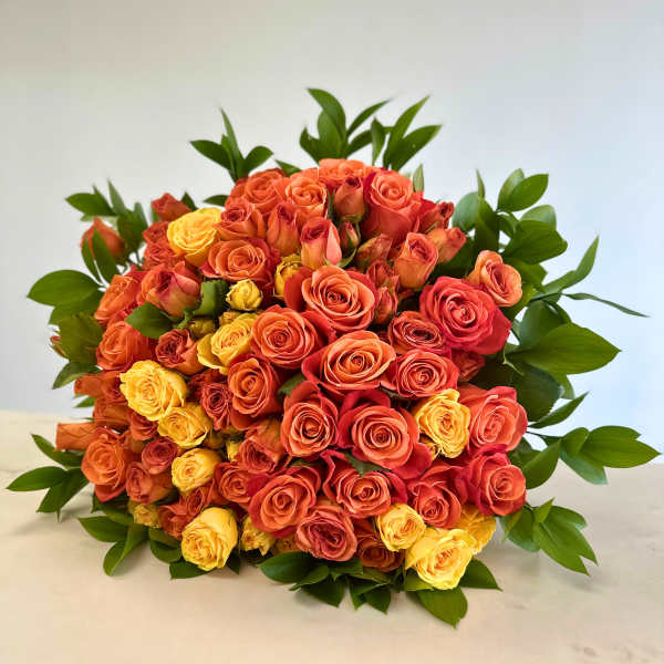 Bouquet of orange, red, and yellow roses with green foliage