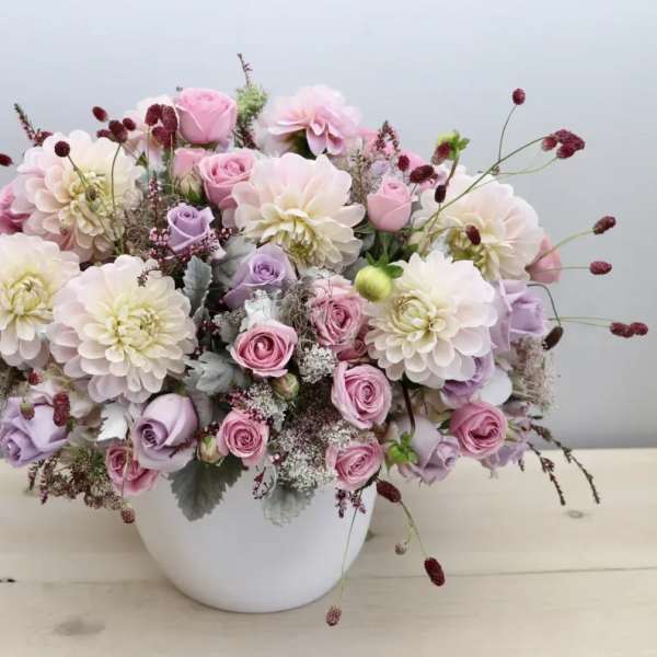 Pink and lavender roses with pale dahlias in a white vase