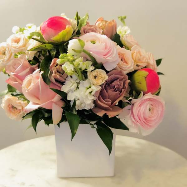 Pink and peach mixed bouquet in a white square vase