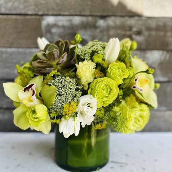 Green and white floral arrangement in a glass vase