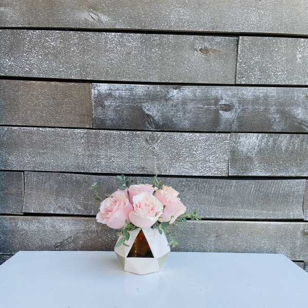 Pink roses in a geometric white vase on a table