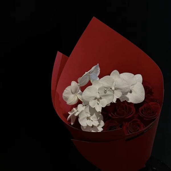 Bouquet of red roses and white orchids wrapped in red paper