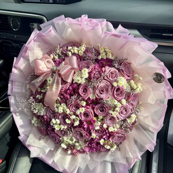Pink rose bouquet with small white filler flowers and a satin bow
