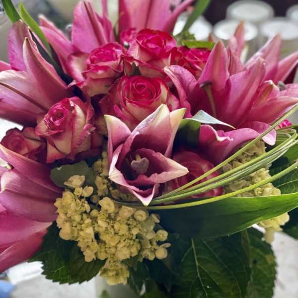 Pink roses and lilies arranged in a clear glass vase