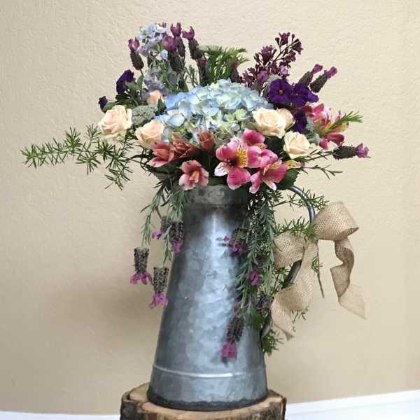 Mixed bouquet in a galvanized pitcher with blue hydrangea and pink flowers