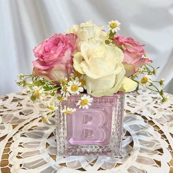 Pink and white roses in a square glass vase with small daisies