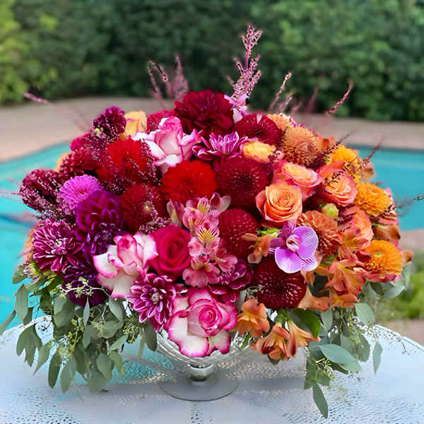 Colorful bouquet of roses, dahlias, and orchids in a silver vase