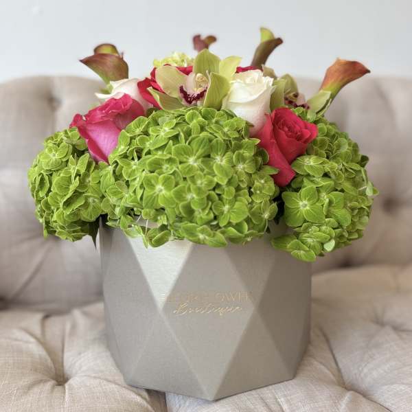 Bouquet of pink and white roses with green hydrangeas in a gray box