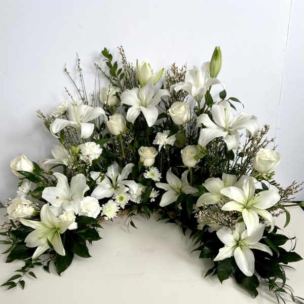 White lilies and roses arranged in a low, wide floral display