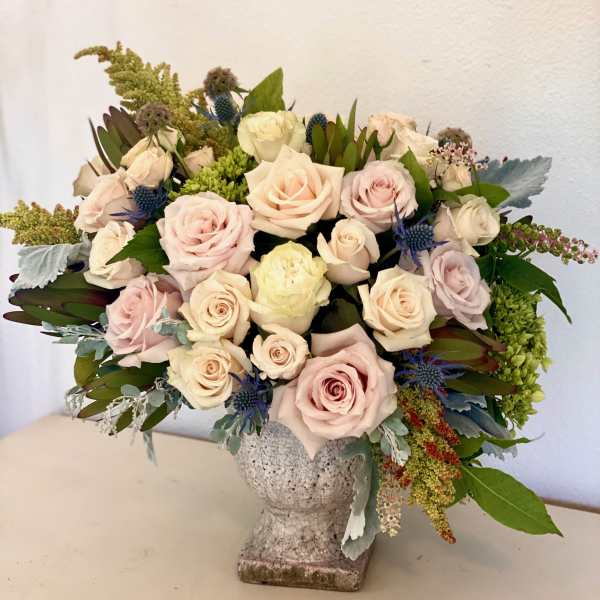 Bouquet of pale pink and cream roses in a textured vase
