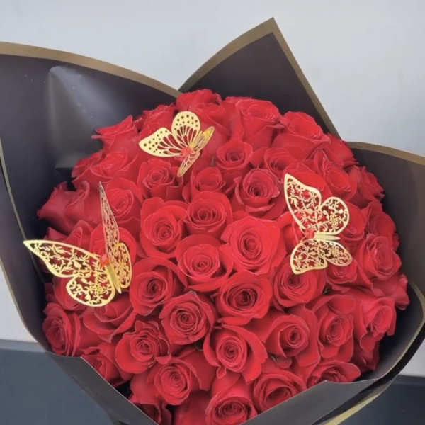 Bouquet of red roses wrapped in black paper with gold butterfly accents