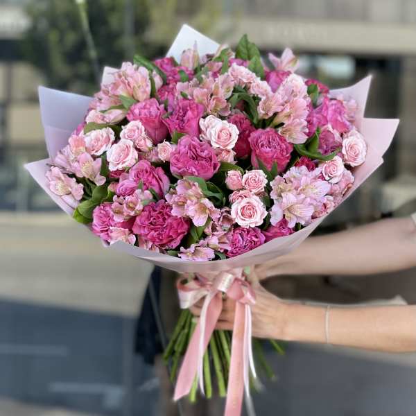 Pink bouquet of roses and alstroemeria wrapped in pale paper