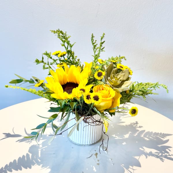 Sunflower and yellow rose arrangement in a white ribbed vase