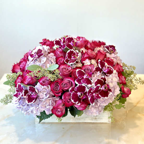 Pink roses and lavender hydrangeas with burgundy orchids in a low wooden box