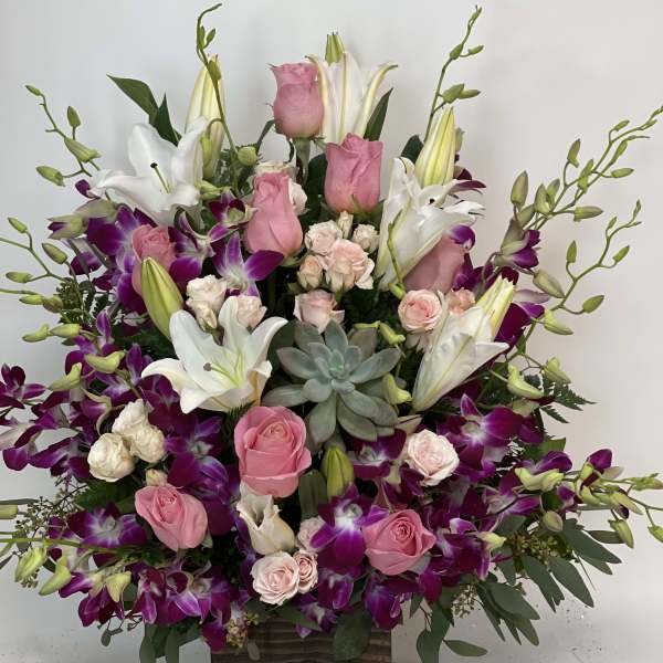 Pink roses and white lilies in a wooden box with purple orchids