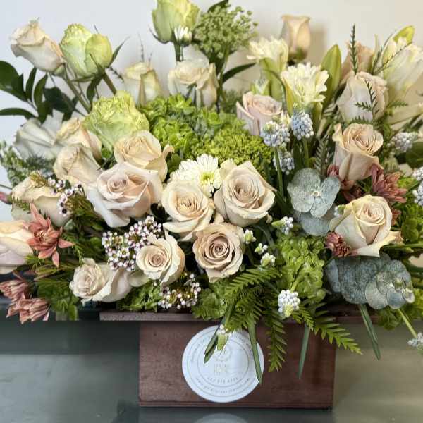Cream roses and green hydrangeas in a wooden box arrangement