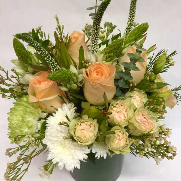 Peach roses and white flowers in a green vase