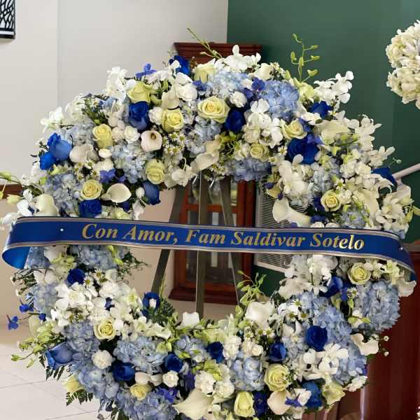 Large blue and white floral wreath on an easel with a memorial ribbon