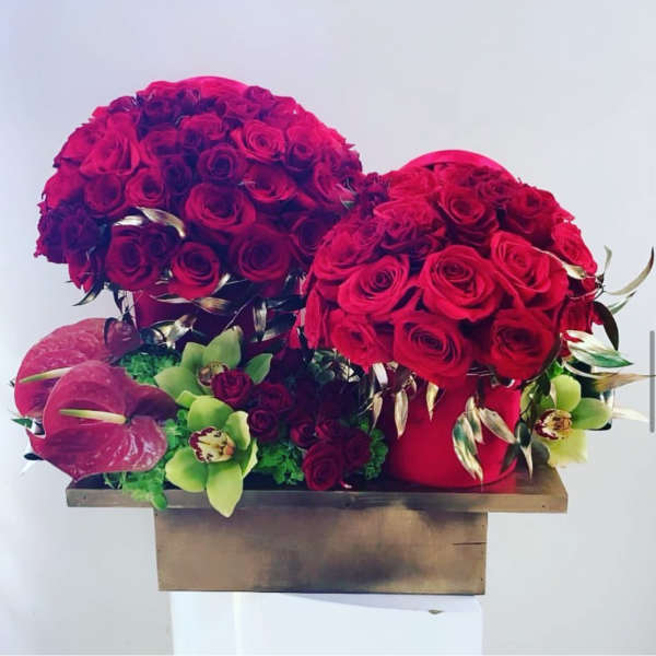 Two red rose arrangements with pink anthuriums in a wooden box