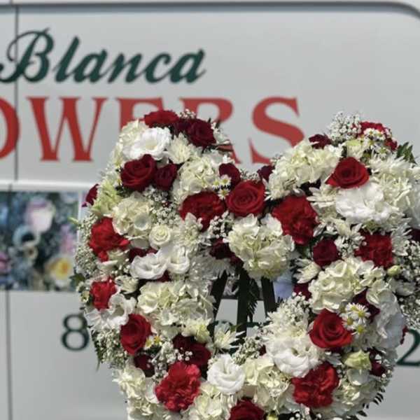 Heart-shaped floral wreath of red and white flowers on a stand