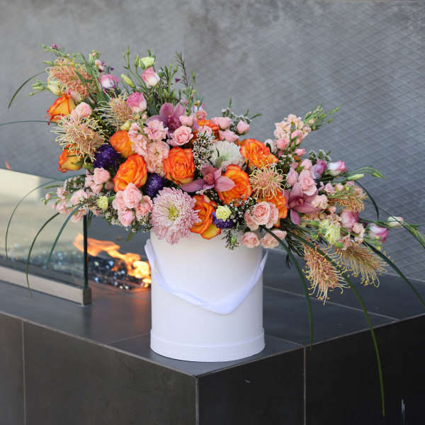 Large mixed floral arrangement in a white vase with pink and orange blooms
