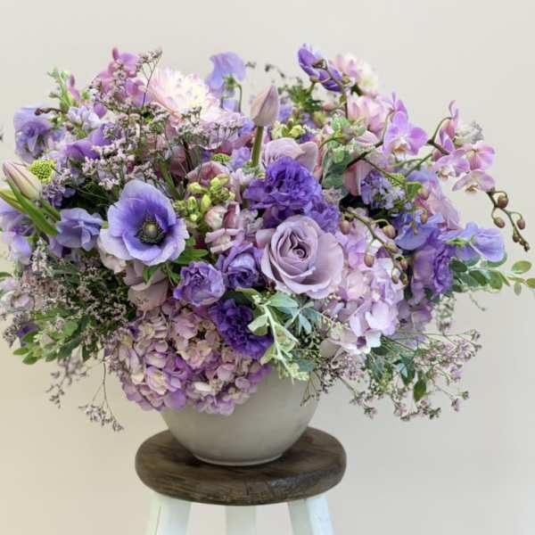 Lavender and purple floral arrangement in a white vase