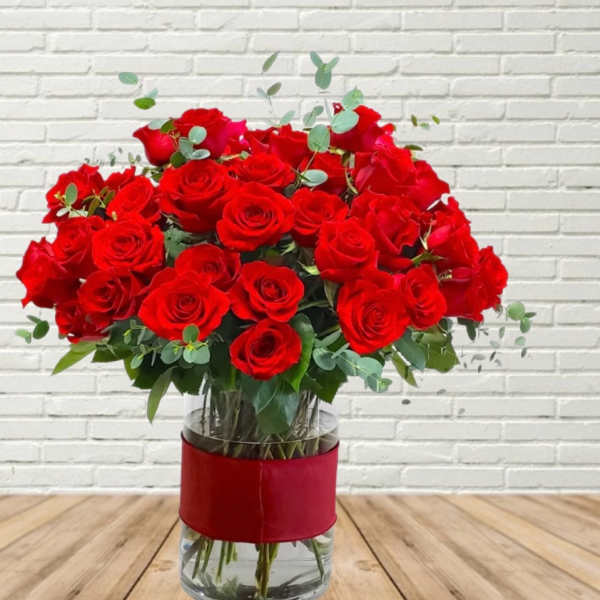 Bouquet of red roses in a clear glass vase with a red wrap