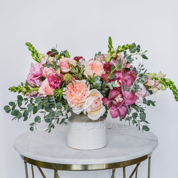 Pink and peach floral arrangement in a white vase