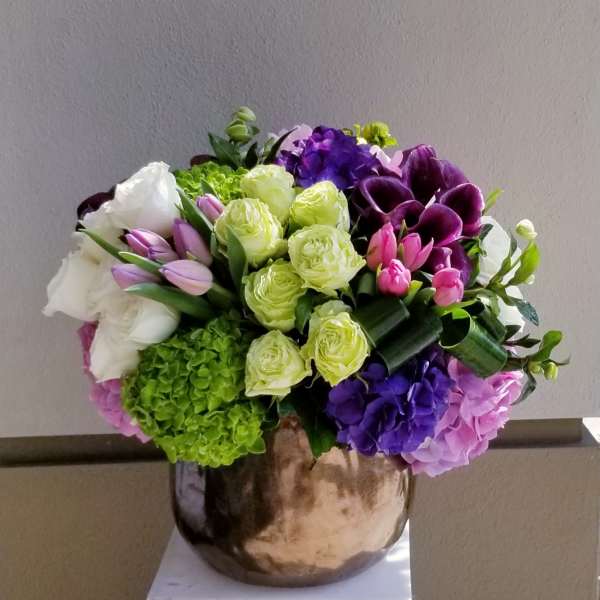 Mixed bouquet of roses, tulips, hydrangeas, and calla lilies in a metallic vase