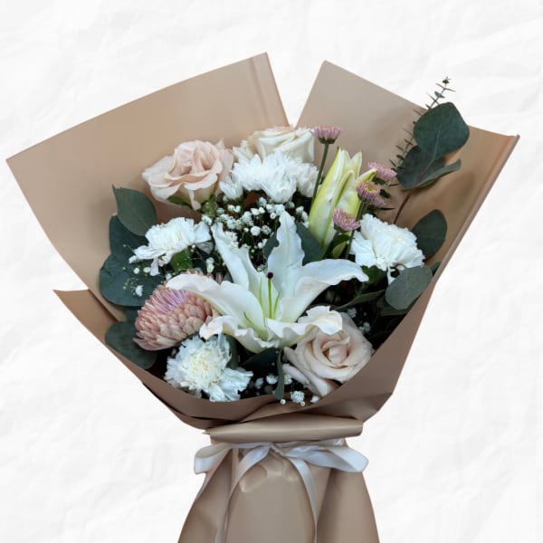 Bouquet of pale roses, white lilies, and chrysanthemums wrapped in tan paper