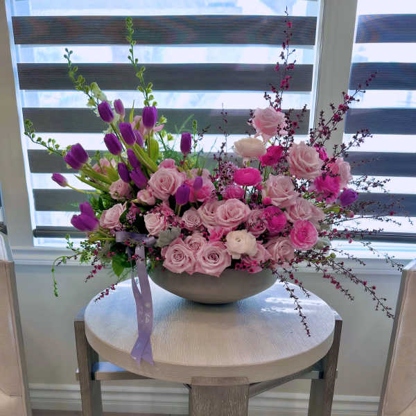 Pink roses and purple tulips arranged in a low bowl