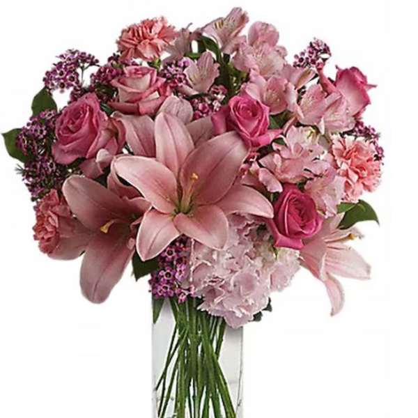 Pink lilies and roses arranged in a clear glass vase
