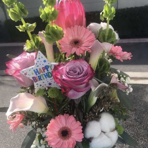 Pink mixed flower bouquet in a blue mug with a birthday card.