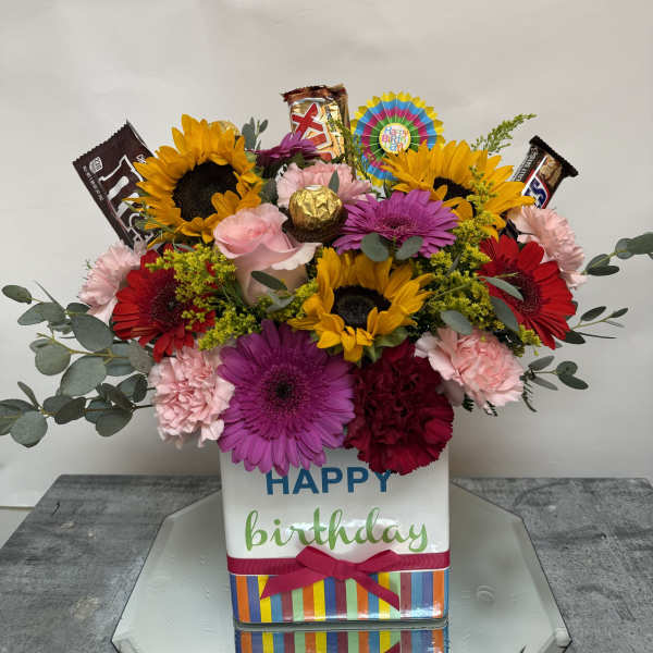 Birthday flower arrangement with sunflowers, gerberas, carnations, and candy bars in a gift box
