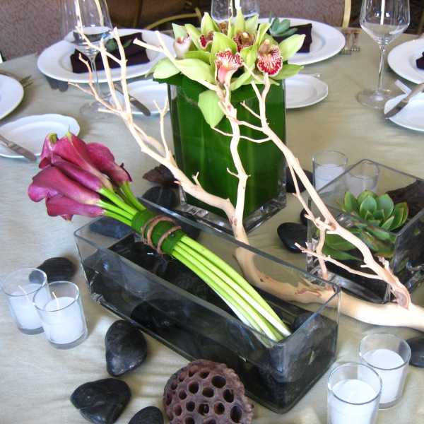 Table centerpiece with orchids, calla lilies, and succulents in glass containers