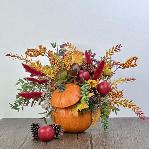 Pumpkin centerpiece with autumn foliage, berries, pinecones, and apples
