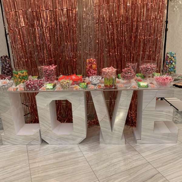 Candy display on a large LOVE sign with a rose-gold backdrop